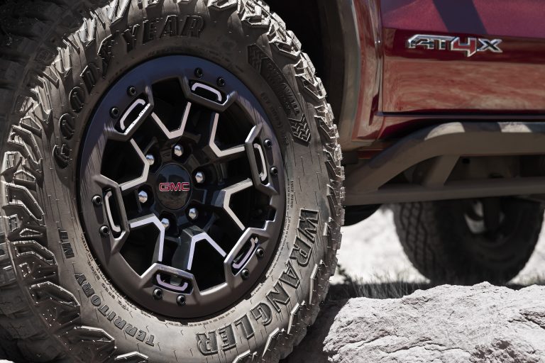 Detail shot of GMC Canyon AT4X with Edition 1 package wheel with GMC logo over uneven terrain.